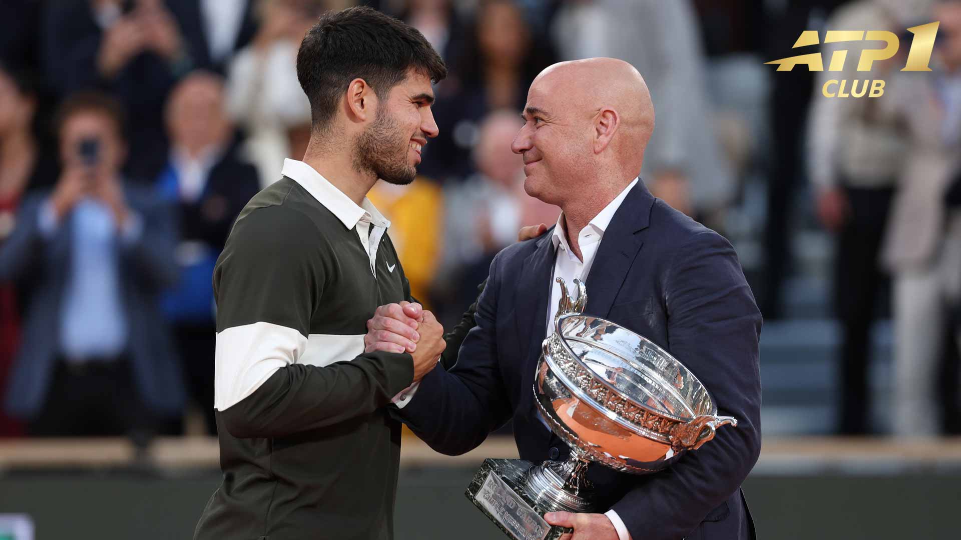 Carlos Alcaraz receives the 2025 Roland Garros trophy, the Coupe des Mousquetaires, from Andre Agassi.